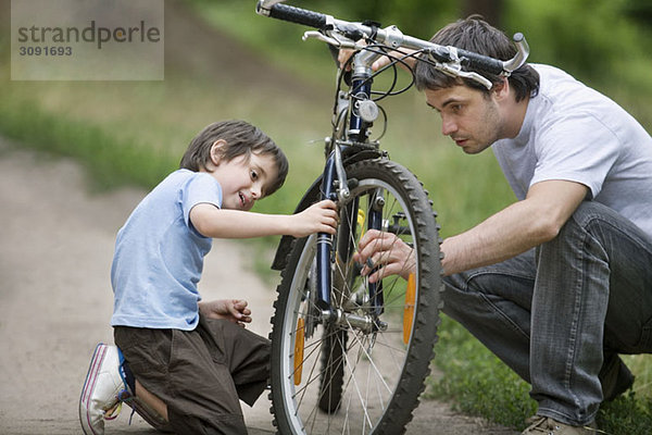Vater und Sohn reparieren ein Fahrrad.
