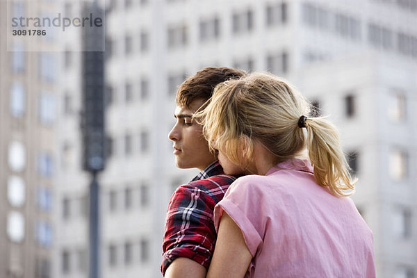 Ein junges Paar  das sich in einer städtischen Umgebung umarmt.