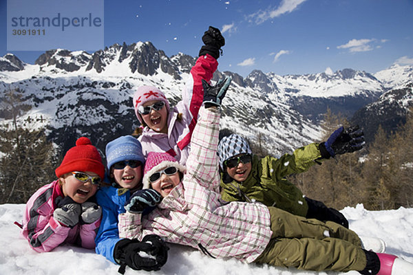 5 Kinder liegen im Schnee.