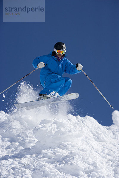 Mann im blauen Overall beim Skifahren.