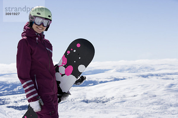 Mädchen posiert mit Snowboard.