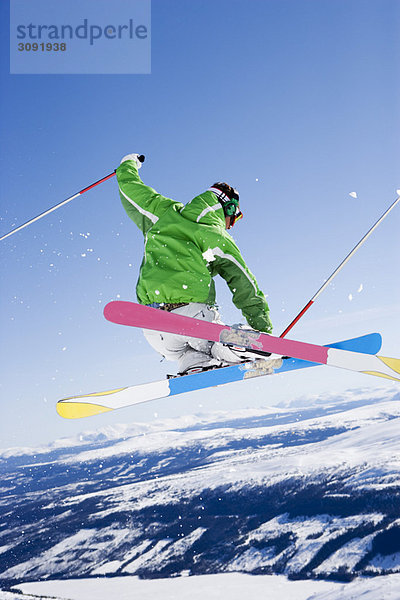 Mann  der sich Skier in der Luft schnappt.