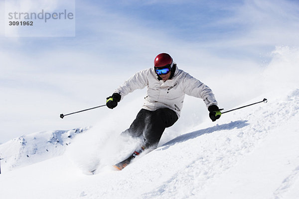 Mann in weiß mit rotem Helm abseits der Piste.