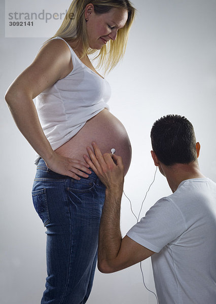 schwangere Frau Mann hört auf Kopfhörer
