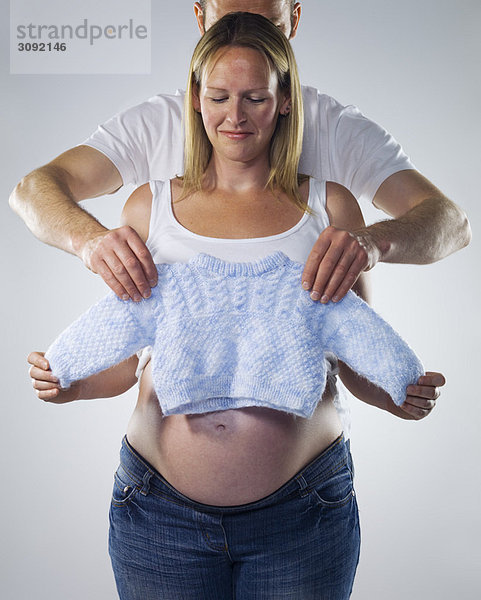 schwangere Frau mit Mann und Babykleidung