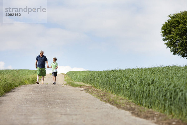 Vater und Sohn gehen eine Straße entlang.