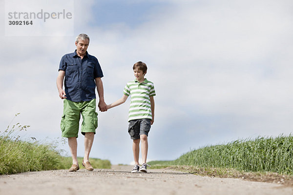 Vater und Sohn gehen eine Straße entlang.