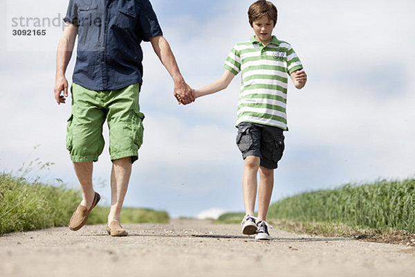 Vater und Sohn gehen eine Straße entlang.