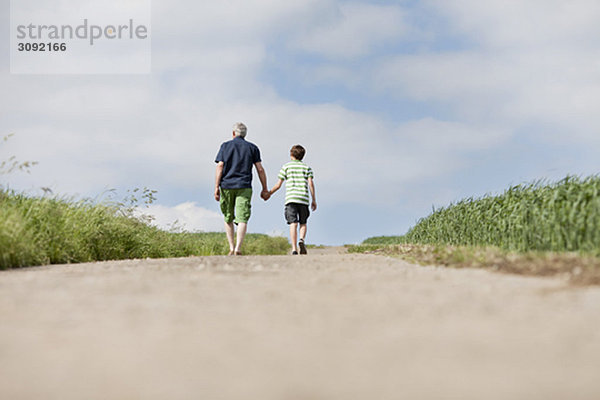 Vater und Sohn gehen eine Straße hinauf.