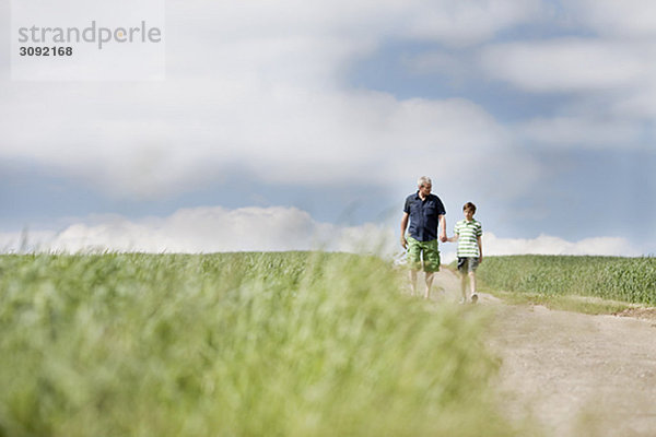 Vater und Sohn gehen eine Straße entlang.