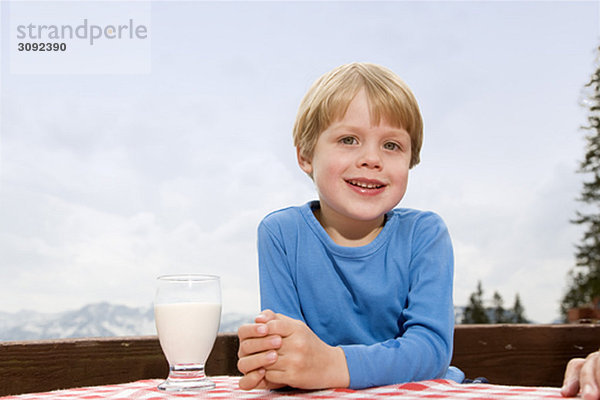 Junge trinkt Milch auf der Berghütte