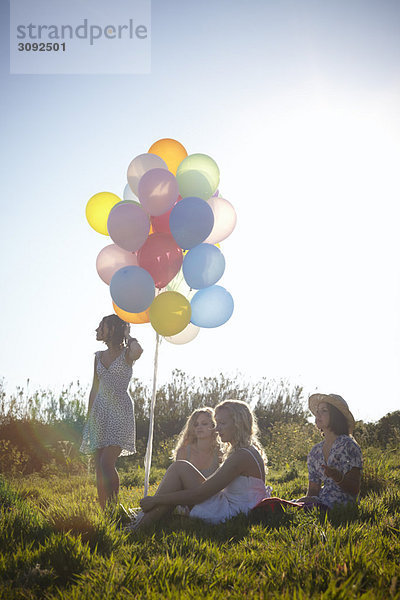 vier Mädchen auf einem Feld mit Luftballons