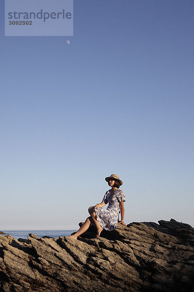 Mädchen auf Felsen am Meer sitzend