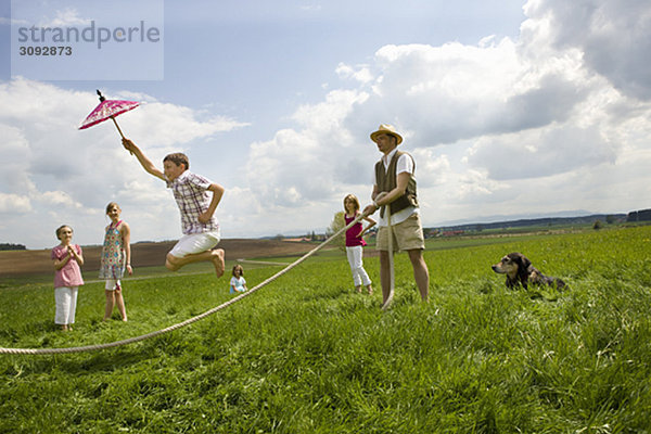 Fröhliche Menschen springen auf dem Land.