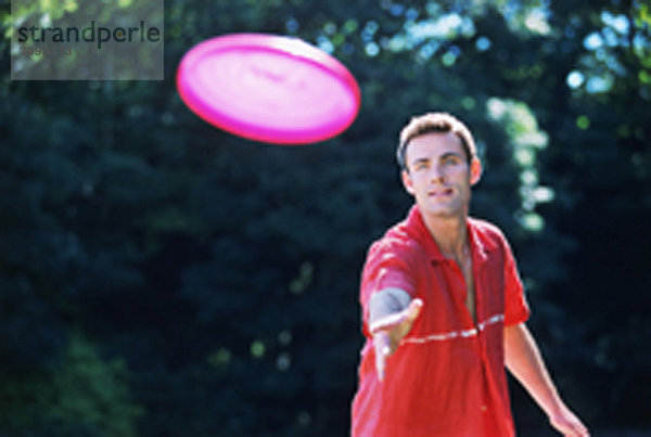 Ein junger Mann  der Frisbee spielt.