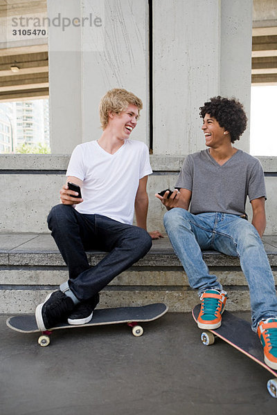Jugendliche mit Handy und Skateboard