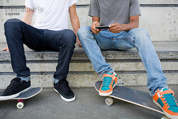 Jugendliche mit Skateboard und Handy