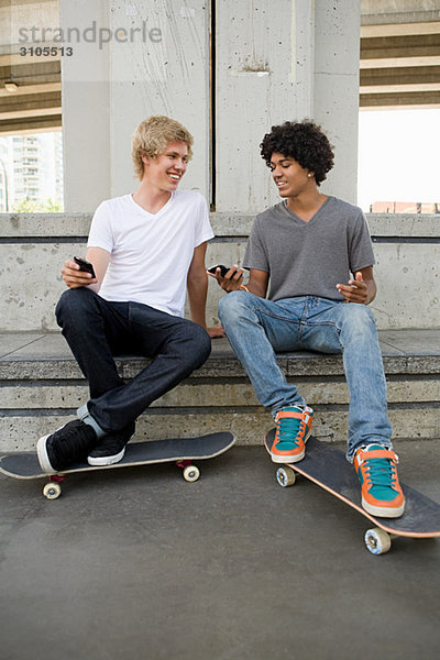 Jugendliche mit Handy und Skateboard