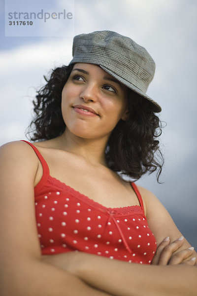 Junge Frau mit Mütze zur Seite gedreht  Arme gefaltet  Portrait