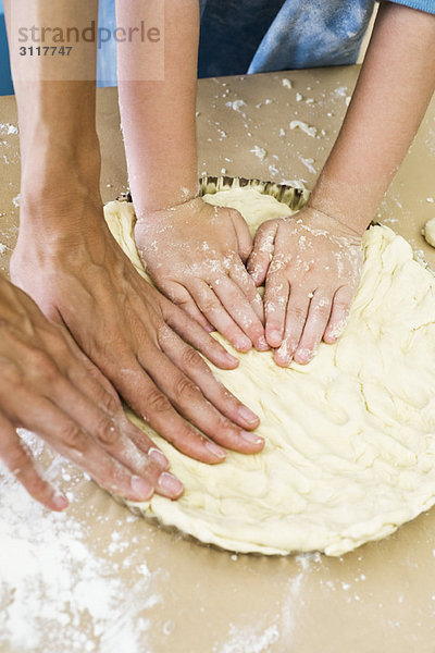 Mutter und Kind machen zusammen Kuchenkruste  Ausschnittdarstellung