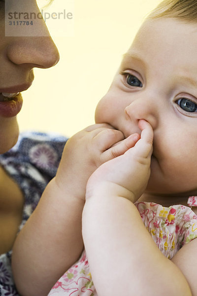 Mutter hält Kleinkind mit Fingern im Mund