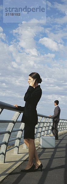 Geschäftsfrau am Ufer Geländer mit dem Handy  Blick auf die Aussicht