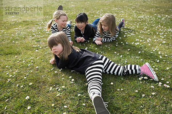 Vier Mädchen auf Gras liegend