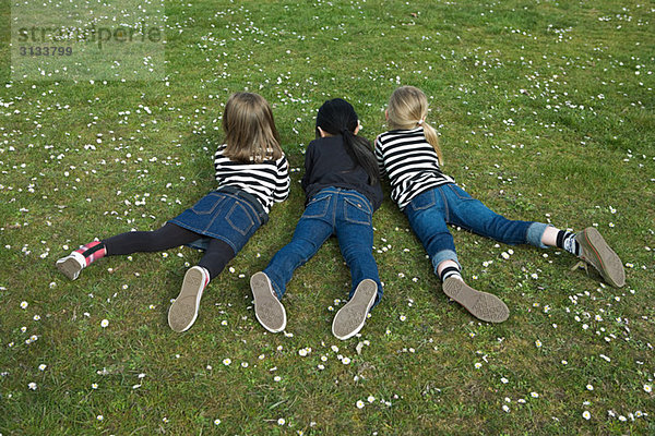 Drei Mädchen auf Gras liegend