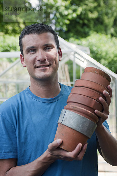 Mann im Garten mit Pflanzentöpfen