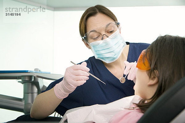 Eine Zahnärztin  die einen Patienten behandelt.