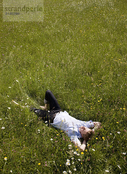 im Gras liegender Mann mit Frühlingsblumen