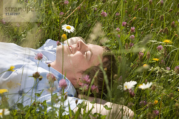 im Gras liegender Mann mit Frühlingsblumen