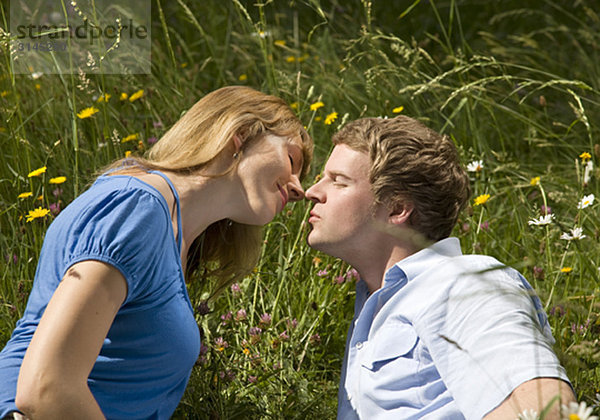 Mann  Frau im Gras küssend mit Blumen