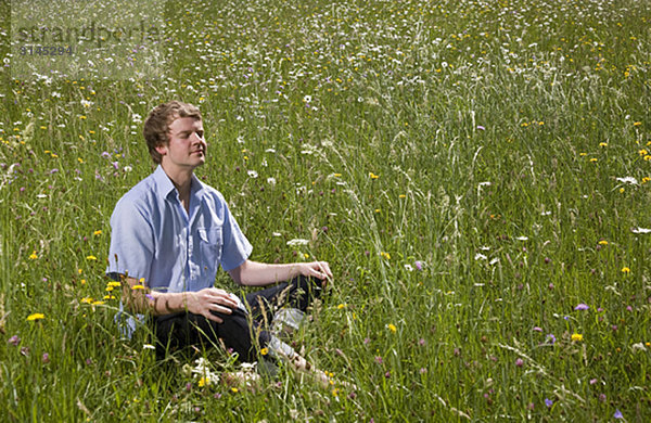 Mann im Gras sitzend mit Frühlingsblumen