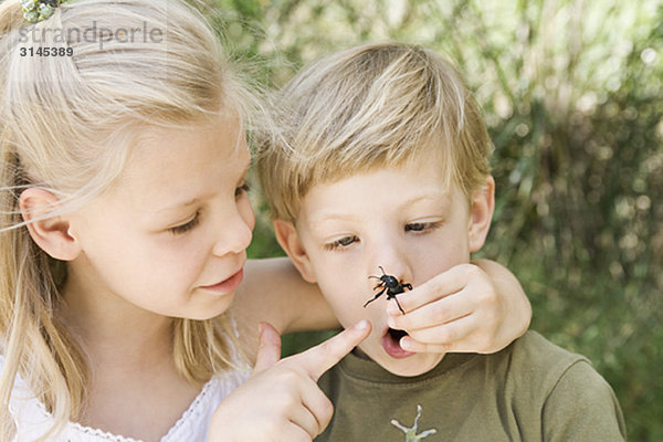 Ein Bruder und eine Schwester mit einem Käfer.
