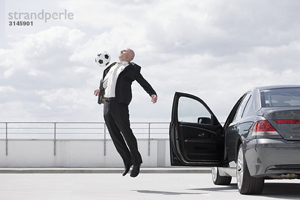 Mann spielt Fußball in der Nähe des Autos