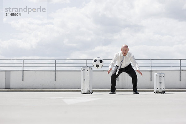 Mann spielt Fußball in der Nähe des Autos