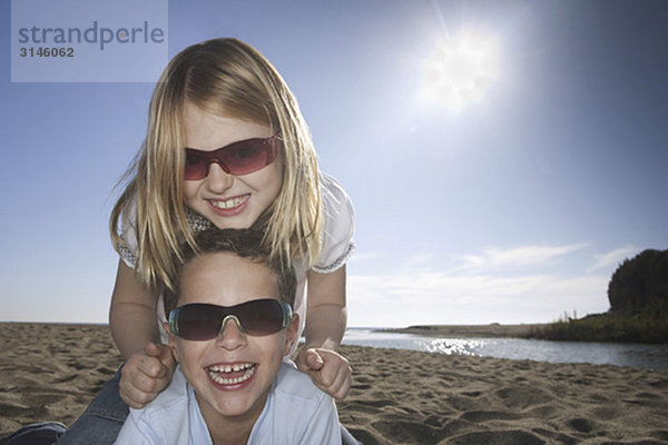 Mädchen und Junge mit Sonnenbrille am Strand