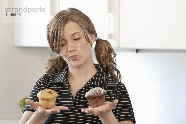 Junge Frau hält zwei Muffins in den Händen
