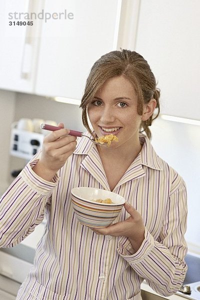 Junge Frau isst ein Schälchen Cornflakes