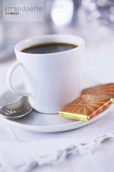 Tasse Kaffee mit Schokoladentäfelchen als Beigabe