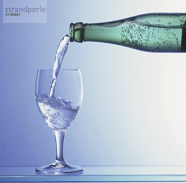 Wasser wird aus Flasche in Glas gegossen