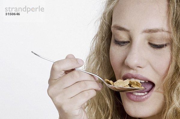 Junge Frau ißt Cornflakes vom Löffel