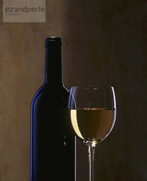 Ein Glas Weisswein und eine Weinflasche