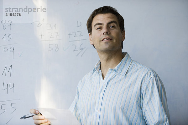 Mathelehrer vor dem Whiteboard  erwartungsvoll schauend
