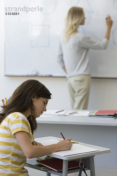 Gymnasiast macht sich Notizen als Lehrer schreibt auf Whiteboard