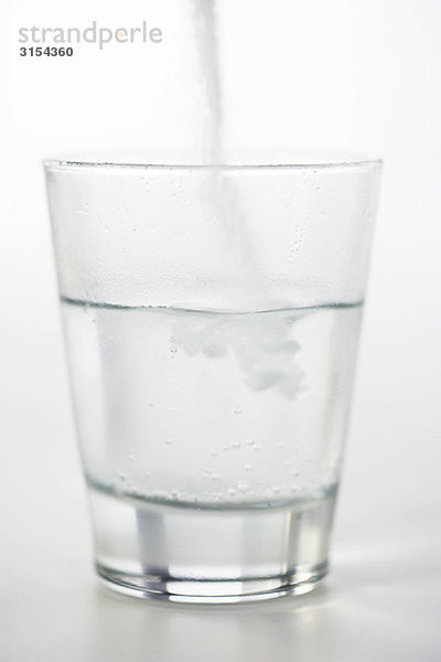 Gießen von Medikamentenpulver in ein Glas Wasser