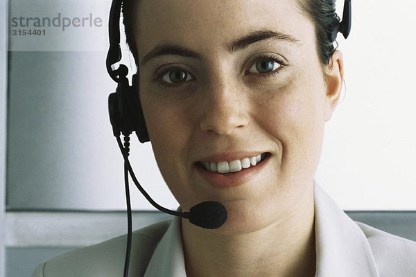 Kundendienstmitarbeiter mit Headset  lächelnd vor der Kamera