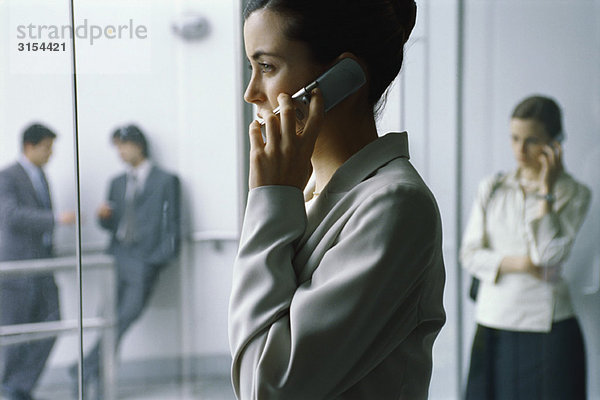 Geschäftsfrau mit Handy in der Lobby  Seitenansicht