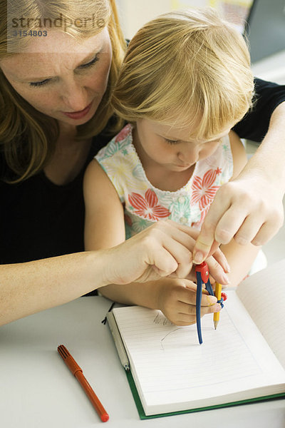 Frau hilft dem kleinen Mädchen beim Zeichnen mit Kompass